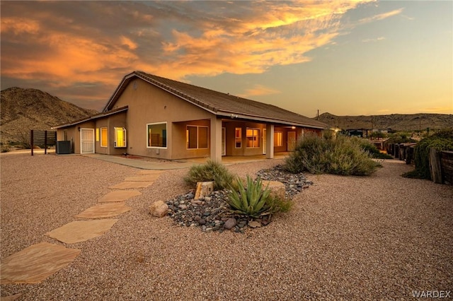 back of property featuring a patio area, central AC, a mountain view, and stucco siding