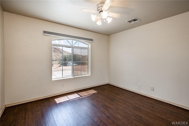 unfurnished room with ceiling fan, dark wood-type flooring, visible vents, and baseboards