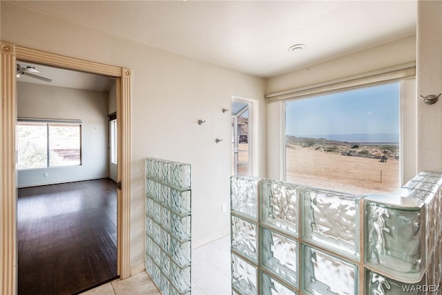 interior space featuring light tile patterned floors, a ceiling fan, and baseboards