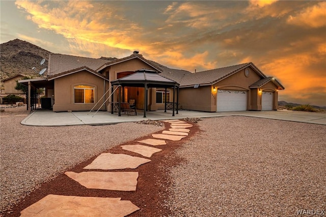 view of front of property with a patio area, an attached garage, a gazebo, and stucco siding