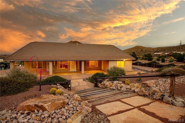 view of front of property featuring stucco siding, a patio, and a mountain view