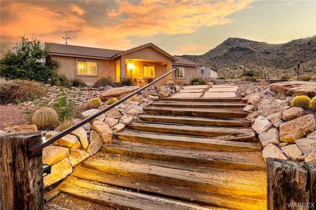 view of front of home with a tile roof, a mountain view, and stucco siding