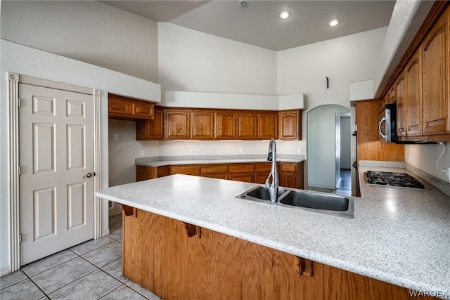 kitchen with a sink, a peninsula, a kitchen bar, and light countertops