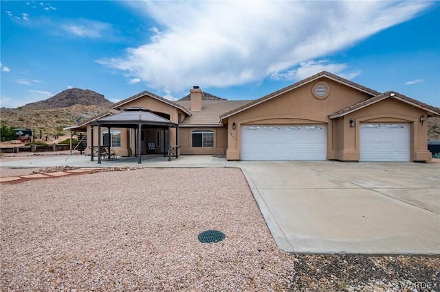 single story home featuring a garage, a chimney, a tiled roof, a mountain view, and stucco siding