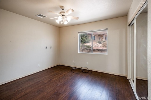 unfurnished bedroom featuring baseboards, visible vents, dark wood finished floors, ceiling fan, and a closet