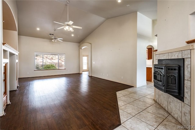 unfurnished living room featuring arched walkways, light wood finished floors, and a ceiling fan