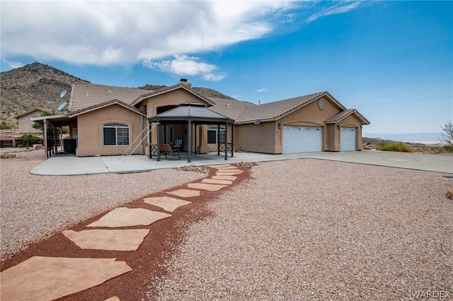 view of front facade with a patio, stucco siding, a gazebo, a garage, and driveway