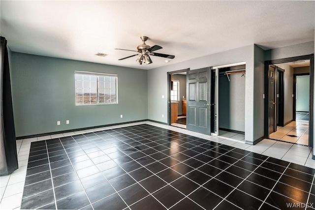 tiled spare room featuring ceiling fan, visible vents, and baseboards