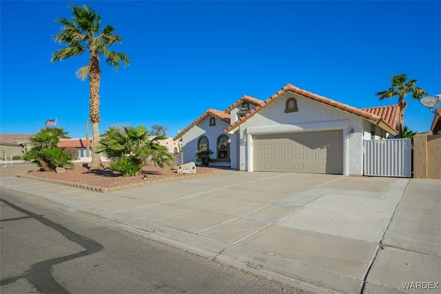 mediterranean / spanish-style house with driveway, an attached garage, a tile roof, and stucco siding