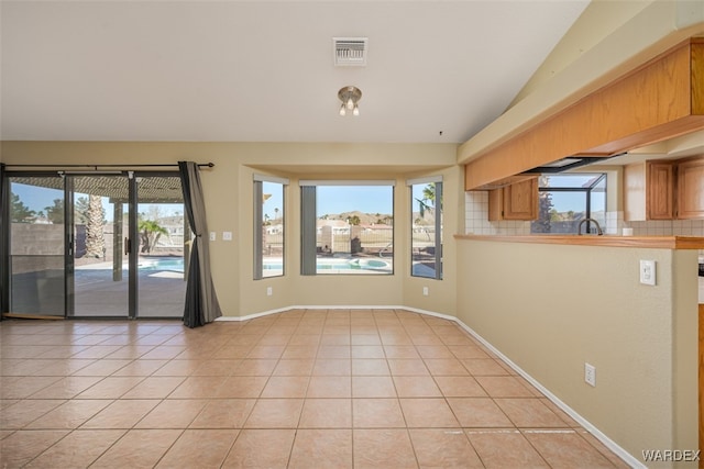 empty room featuring light tile patterned flooring, plenty of natural light, and visible vents