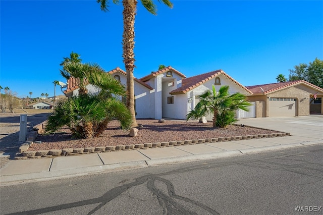 mediterranean / spanish-style home with a garage, a tile roof, concrete driveway, and stucco siding