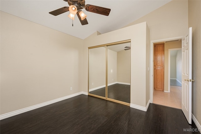 unfurnished bedroom with baseboards, dark wood finished floors, a ceiling fan, vaulted ceiling, and a closet