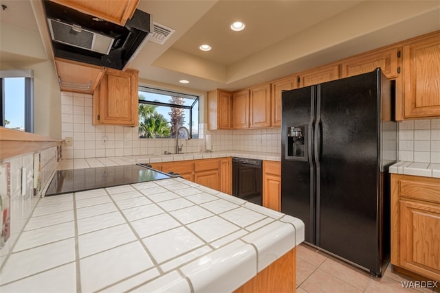 kitchen with tile countertops, ventilation hood, black appliances, a sink, and light tile patterned flooring