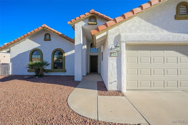 mediterranean / spanish home with a garage, a tiled roof, and stucco siding