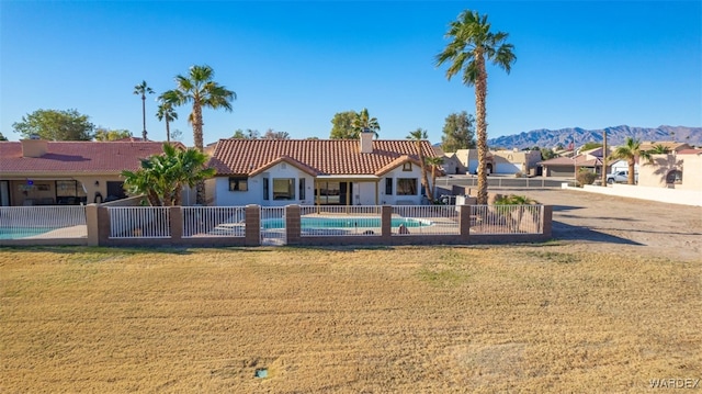 rear view of property with a mountain view, fence, a tiled roof, a residential view, and a fenced in pool