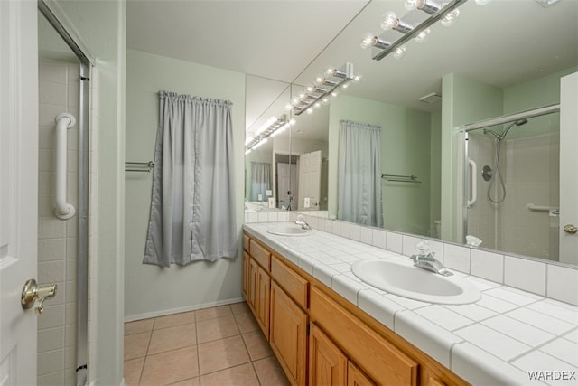 full bath with double vanity, a sink, a shower stall, and tile patterned floors