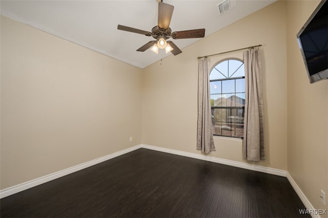 empty room with dark wood-type flooring, a ceiling fan, visible vents, vaulted ceiling, and baseboards