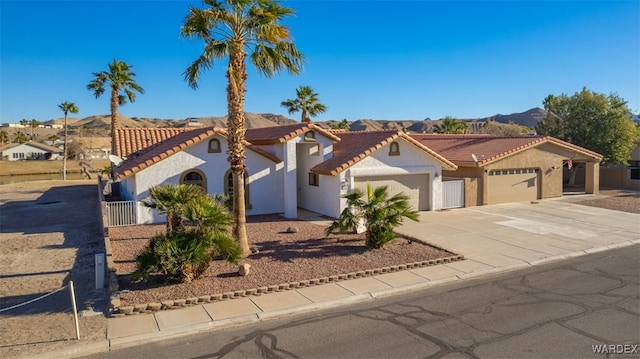 mediterranean / spanish-style home featuring a mountain view, a garage, a tile roof, driveway, and stucco siding