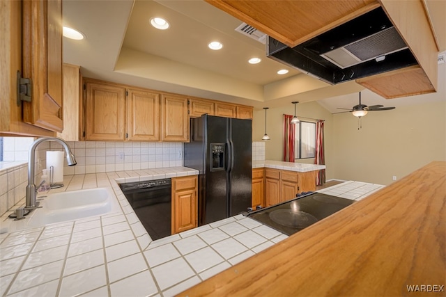 kitchen with tile countertops, a peninsula, a sink, black appliances, and tasteful backsplash