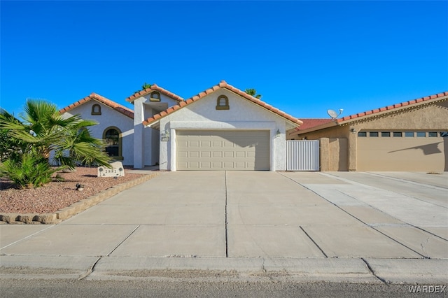 mediterranean / spanish house featuring a garage, concrete driveway, a tile roof, and stucco siding