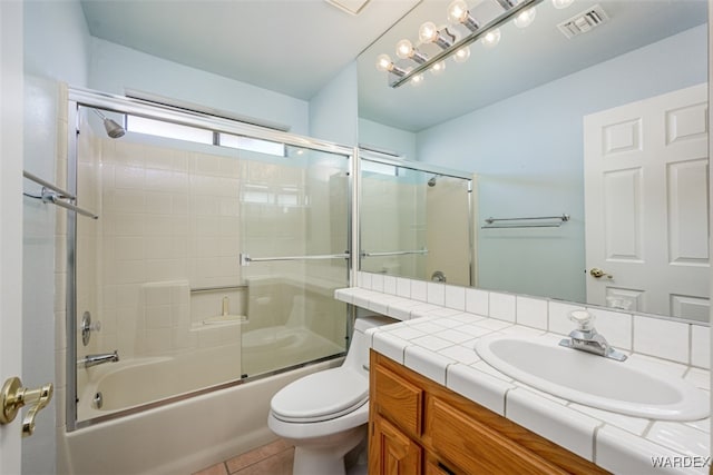 bathroom with tile patterned flooring, toilet, visible vents, vanity, and combined bath / shower with glass door