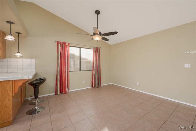 interior space featuring vaulted ceiling, light tile patterned floors, a ceiling fan, and baseboards