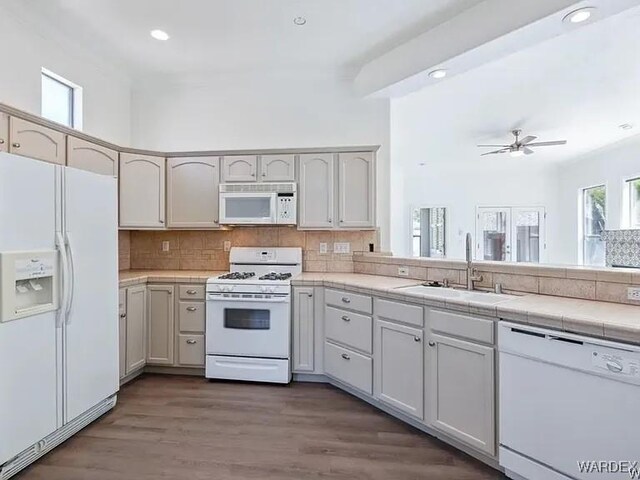 kitchen featuring a sink, white appliances, tasteful backsplash, and wood finished floors