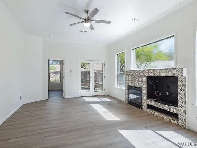 unfurnished living room featuring visible vents, baseboards, a tiled fireplace, ornamental molding, and wood finished floors