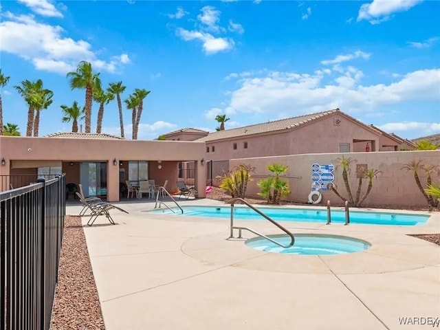 pool with a patio, a community hot tub, and fence