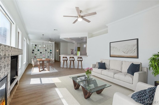 living room featuring visible vents, ornamental molding, a ceiling fan, wood finished floors, and a high end fireplace