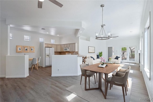 dining room with visible vents, crown molding, baseboards, light wood-type flooring, and ceiling fan with notable chandelier