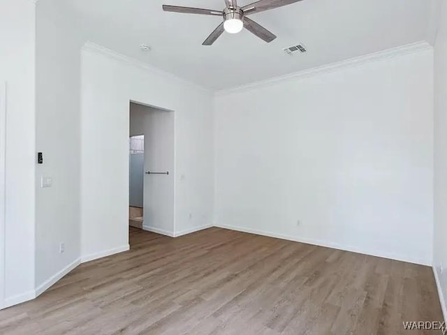 empty room with visible vents, crown molding, baseboards, ceiling fan, and wood finished floors