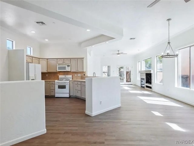 kitchen with ceiling fan with notable chandelier, tasteful backsplash, open floor plan, white appliances, and a peninsula