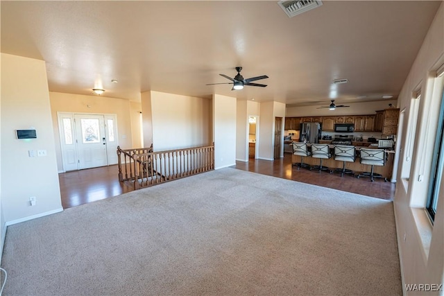 unfurnished living room featuring visible vents and dark colored carpet