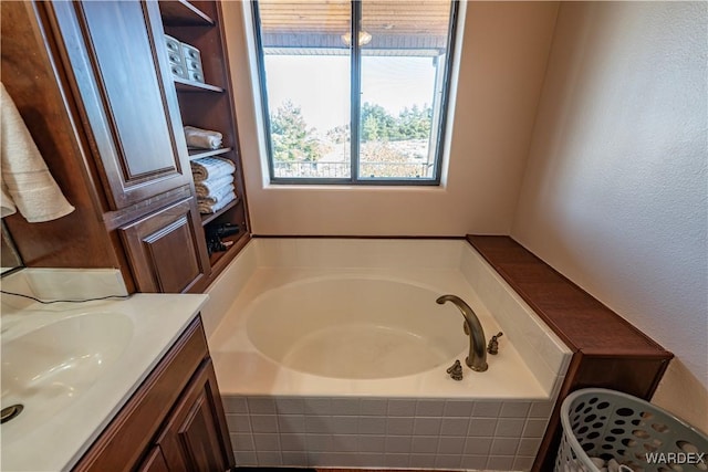 bathroom with a garden tub, a textured wall, and vanity