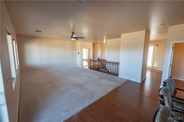 unfurnished room with ceiling fan, wood finished floors, visible vents, and baseboards