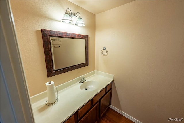 bathroom with baseboards, wood finished floors, and vanity