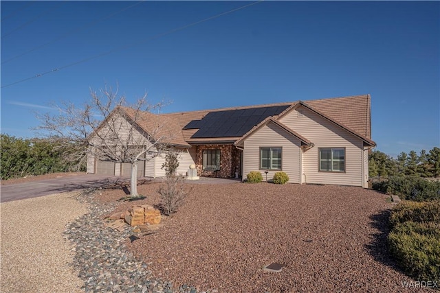 view of front of property with a garage, driveway, and solar panels