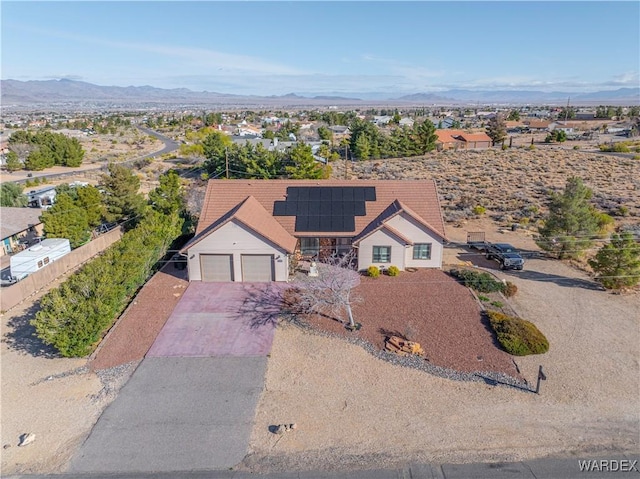 view of front of house with an attached garage, roof mounted solar panels, a mountain view, fence, and driveway