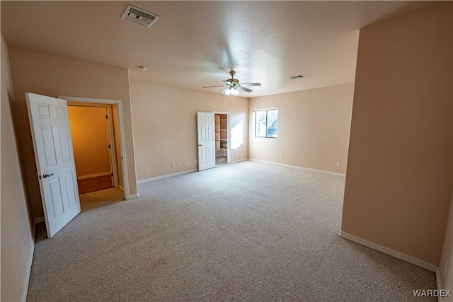 empty room featuring carpet floors, baseboards, visible vents, and ceiling fan