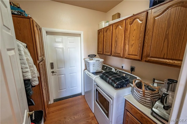 clothes washing area featuring cabinet space, washer and clothes dryer, and wood finished floors