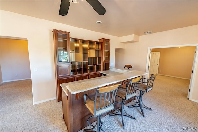 interior space with a ceiling fan, light colored carpet, visible vents, and baseboards