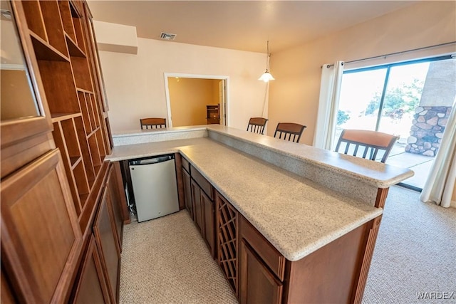 kitchen with dishwashing machine, pendant lighting, light carpet, a peninsula, and a kitchen breakfast bar