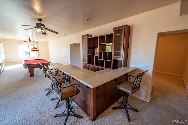 interior space featuring carpet floors, light countertops, a peninsula, and a kitchen breakfast bar