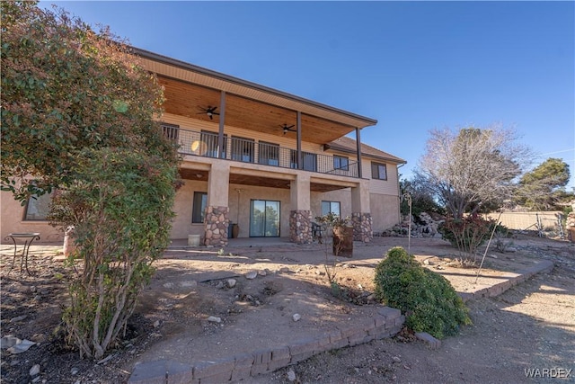 rear view of property featuring a balcony, a ceiling fan, and stucco siding