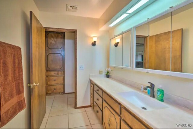 bathroom with baseboards, vanity, visible vents, and tile patterned floors