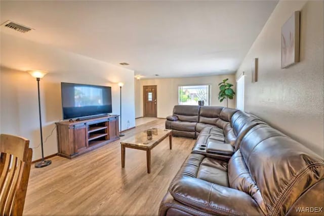 living room with light wood-style flooring, visible vents, and baseboards