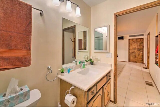 half bathroom with toilet, vanity, tile patterned flooring, and visible vents