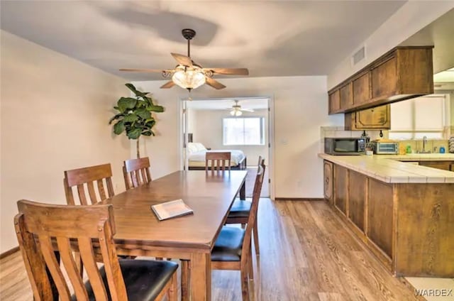 dining space featuring baseboards, light wood finished floors, and a toaster