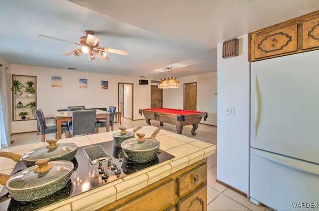 kitchen featuring tile countertops, light tile patterned flooring, billiards, freestanding refrigerator, and brown cabinets